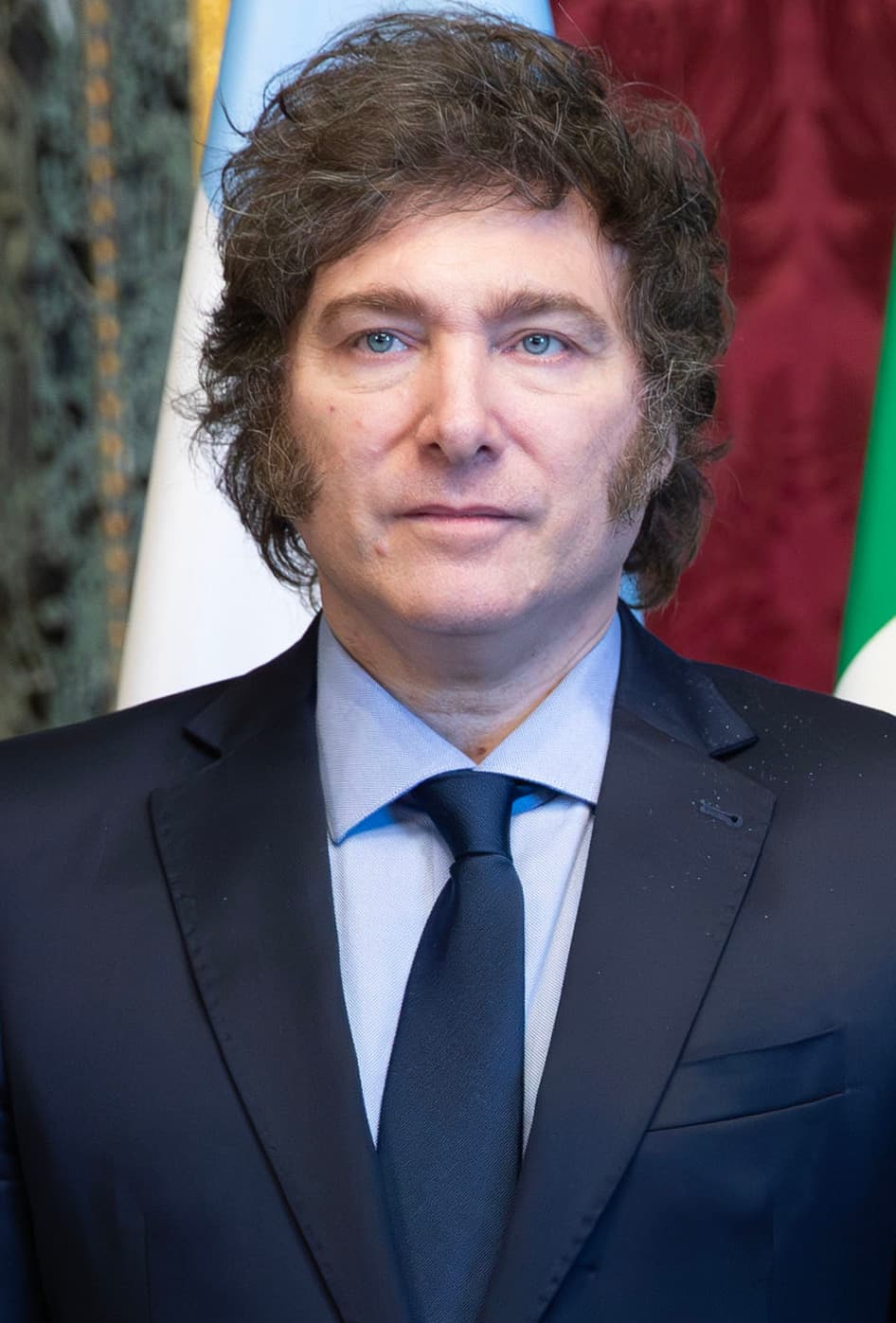 Homme politique en costume devant des drapeaux