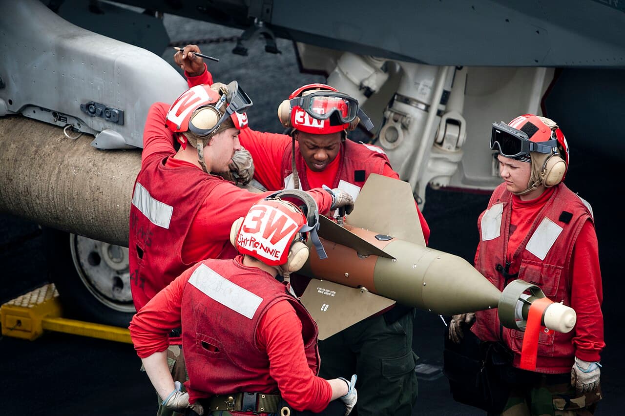 Militaires chargeant une bombe sous un avion