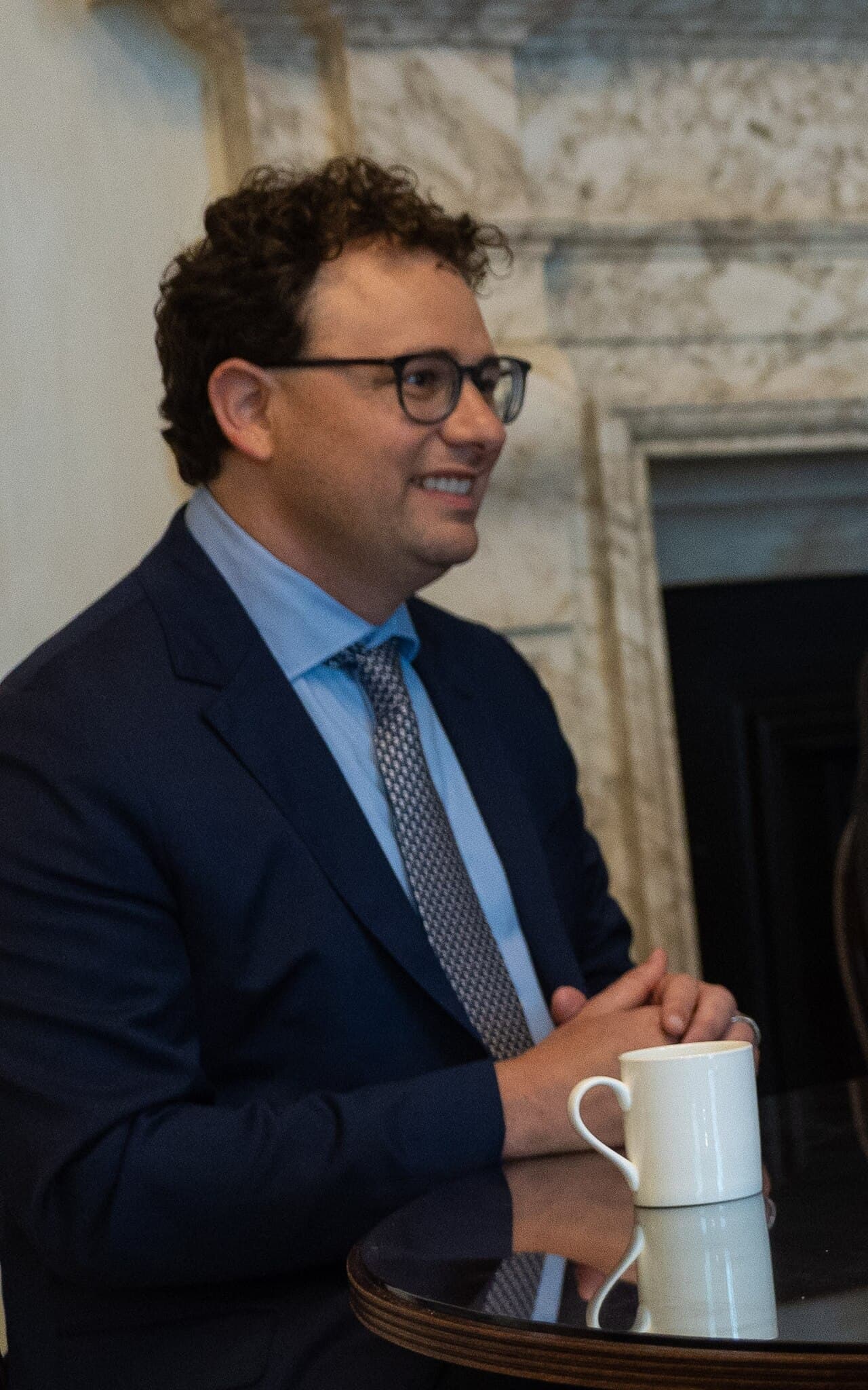 Homme en costume avec lunettes, tenant une tasse