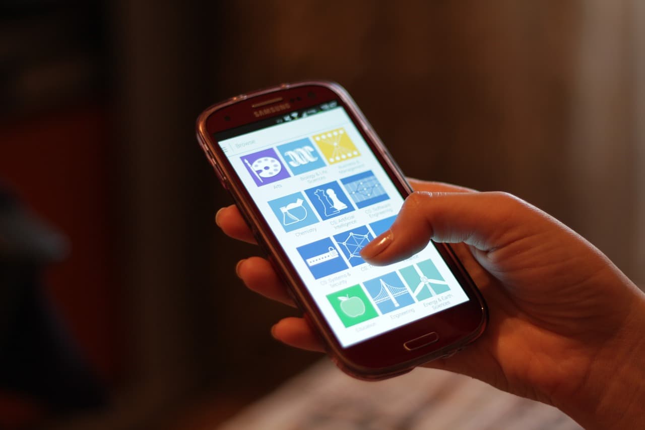 Main tenant un smartphone affichant des applications