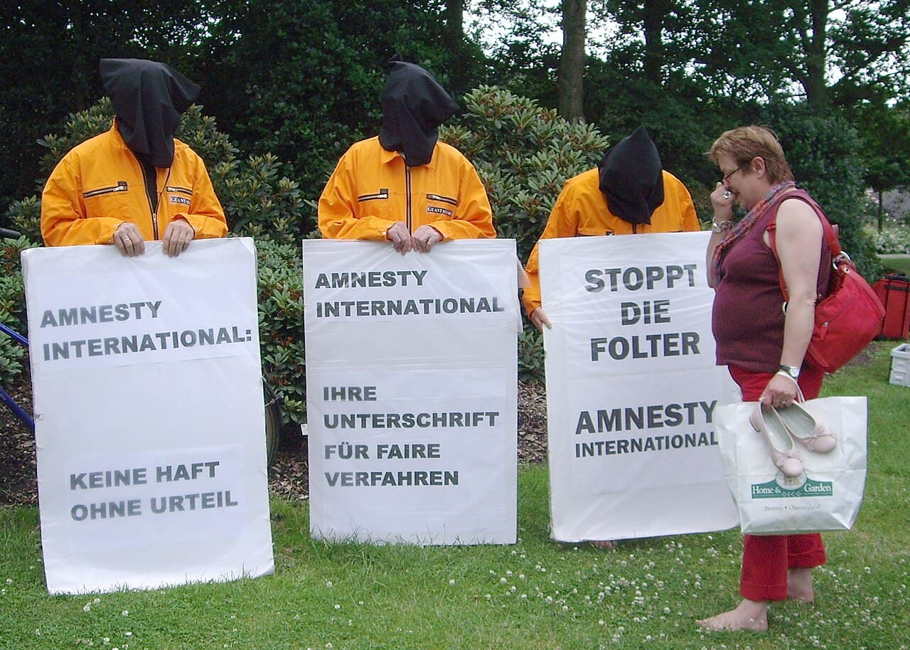 Militants masqués brandissant des pancartes contre la torture