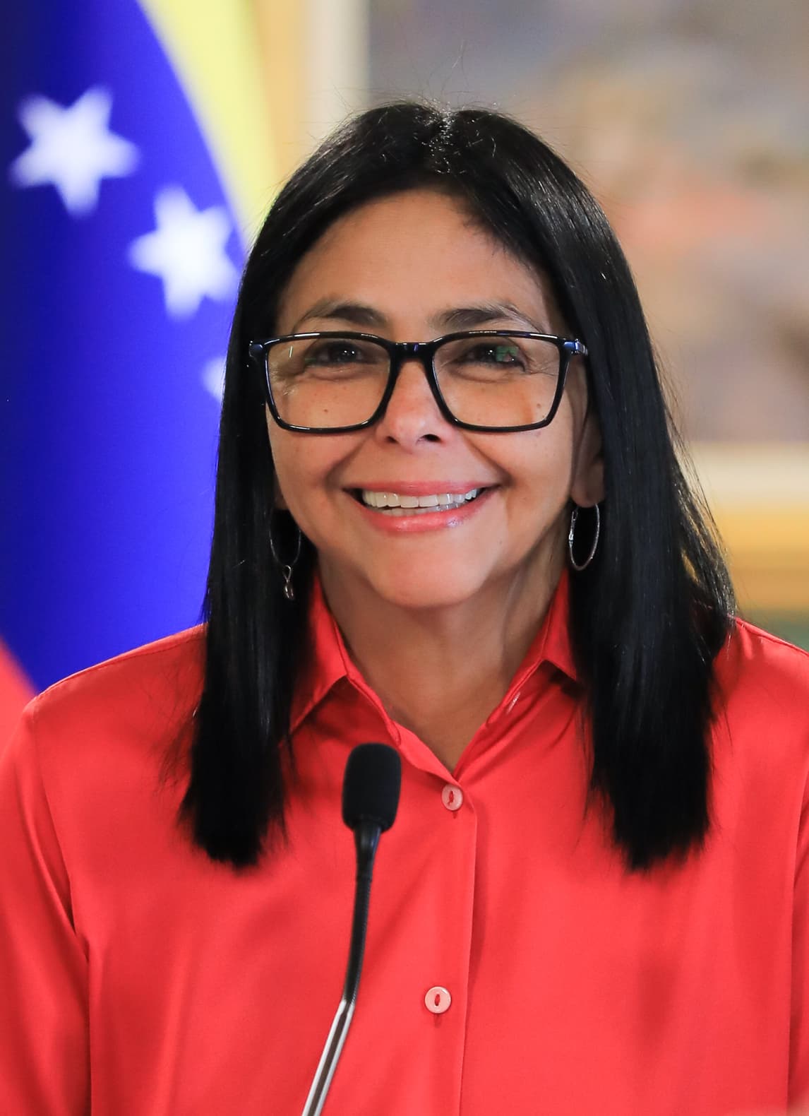 Femme en chemise rouge devant un drapeau