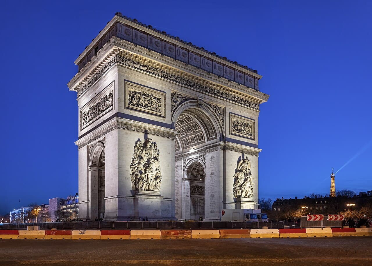 Arc monumental illuminé derrière des barrières de chantier