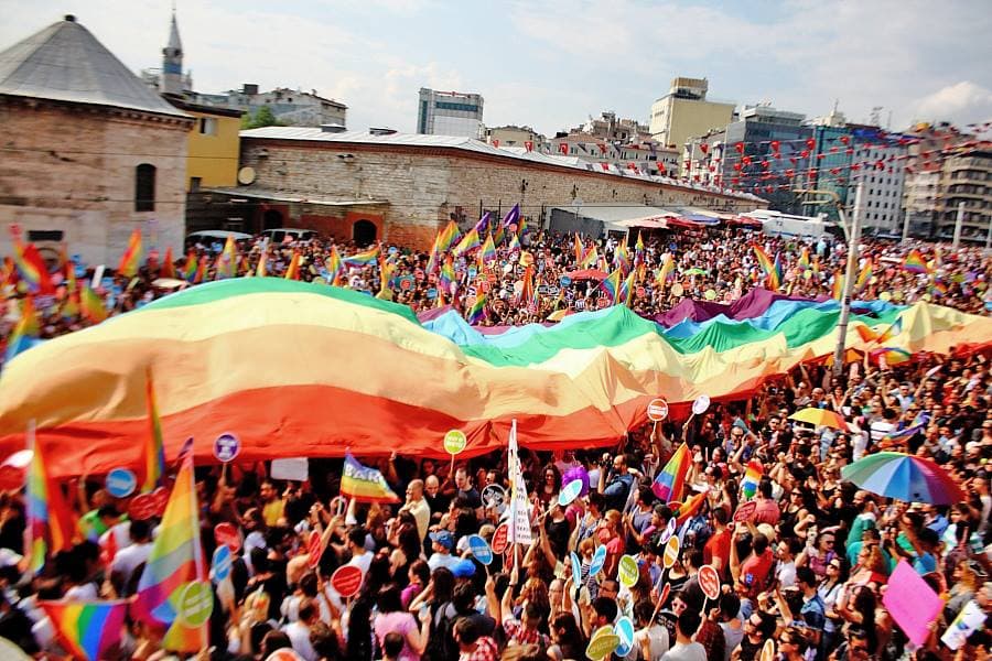 Foule brandissant un immense drapeau arc-en-ciel